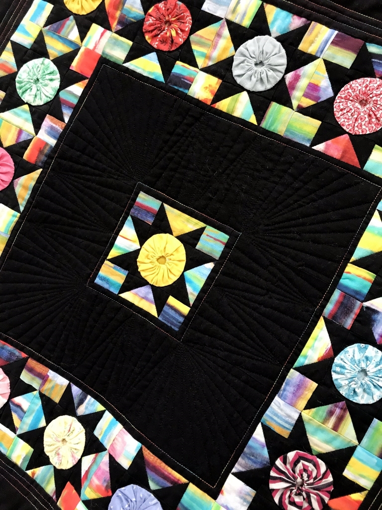 Detail of Rainbow Yo-yos quilt by Linda Fleschner.