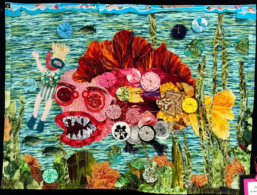 Art quilt depicting improvisationally appliqued fish with big teeth.