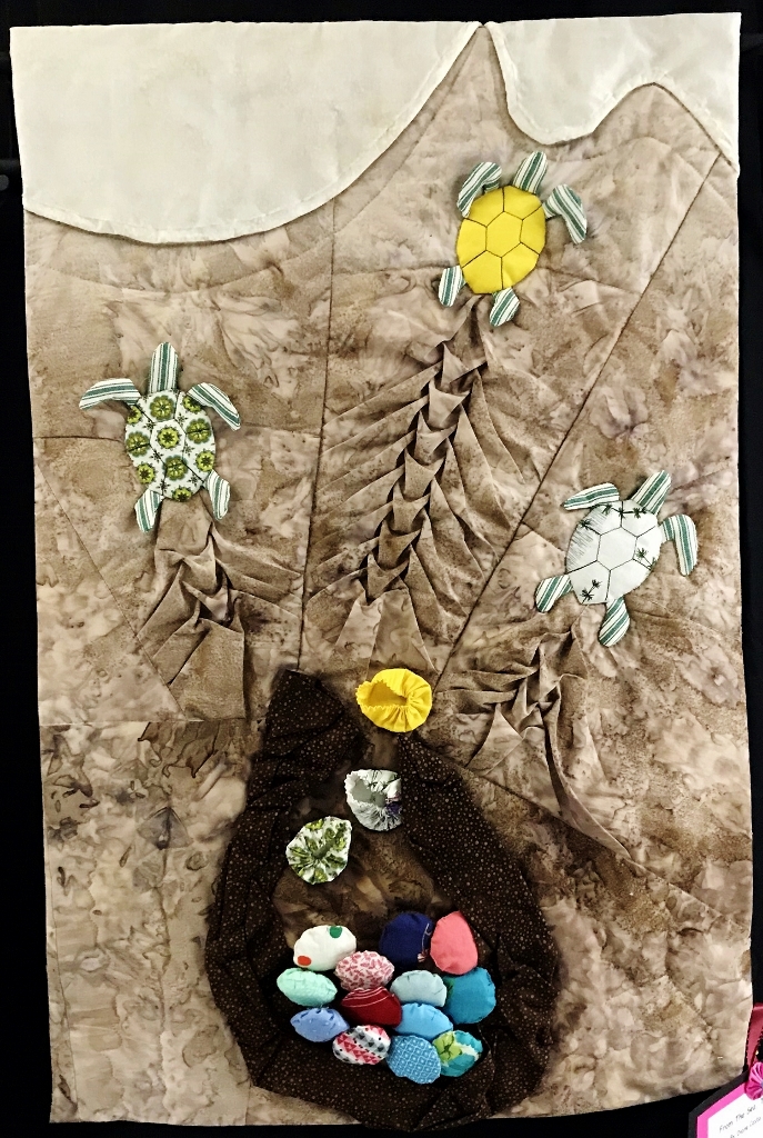 Art quilt depicting sea life, using yo-yos and smocking techniques.