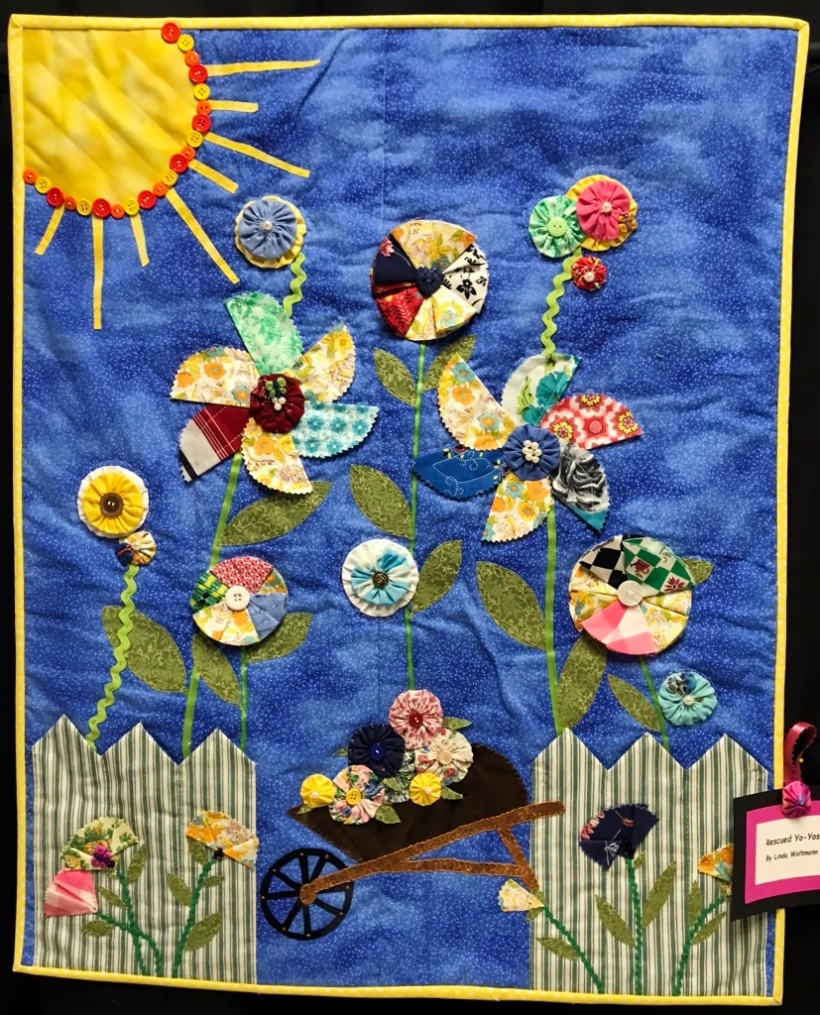 Art quilt with blue background and garden imagery.